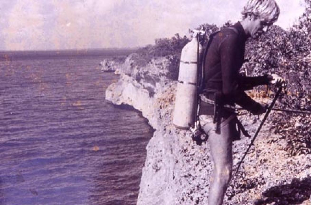 Bruce Bowker gears up in full scuba gear to rappel down the a Bonaire cliff