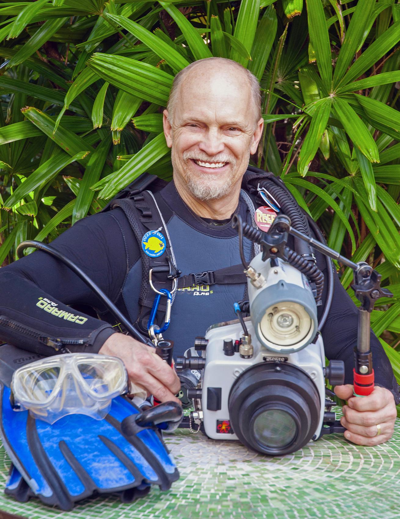 A person in a wet suit holding a camera