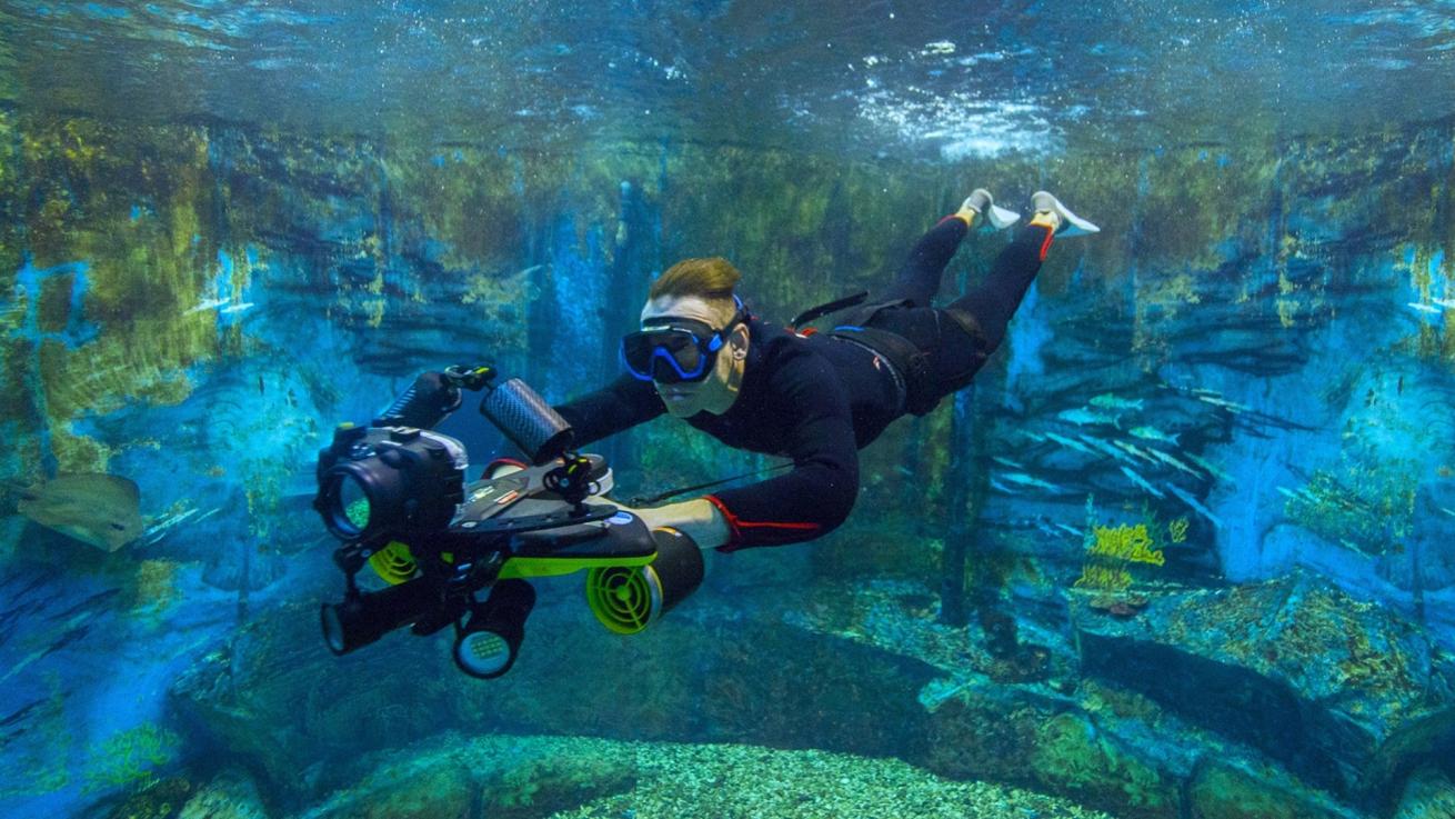 An underwater photographer using an underwater scooter.