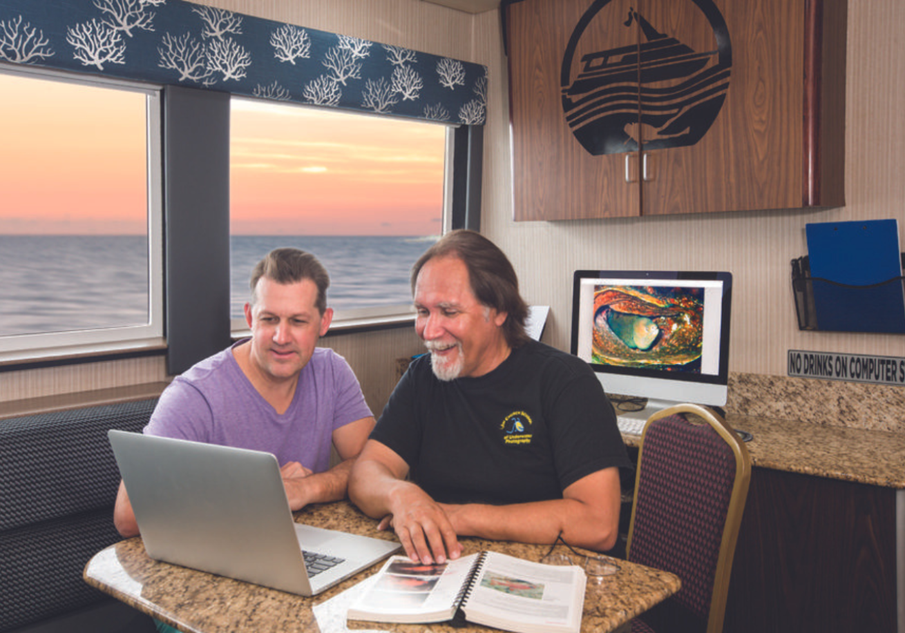 Men sitting at a table looking at a computer