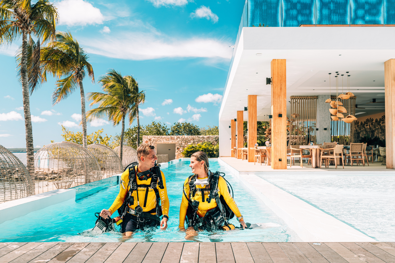 A person and person wearing scuba gear in a pool