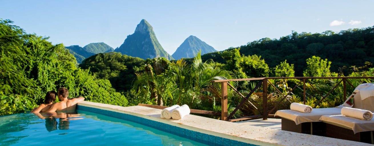 A pool with towels and mountains in the background with Anse Chastanet in the background