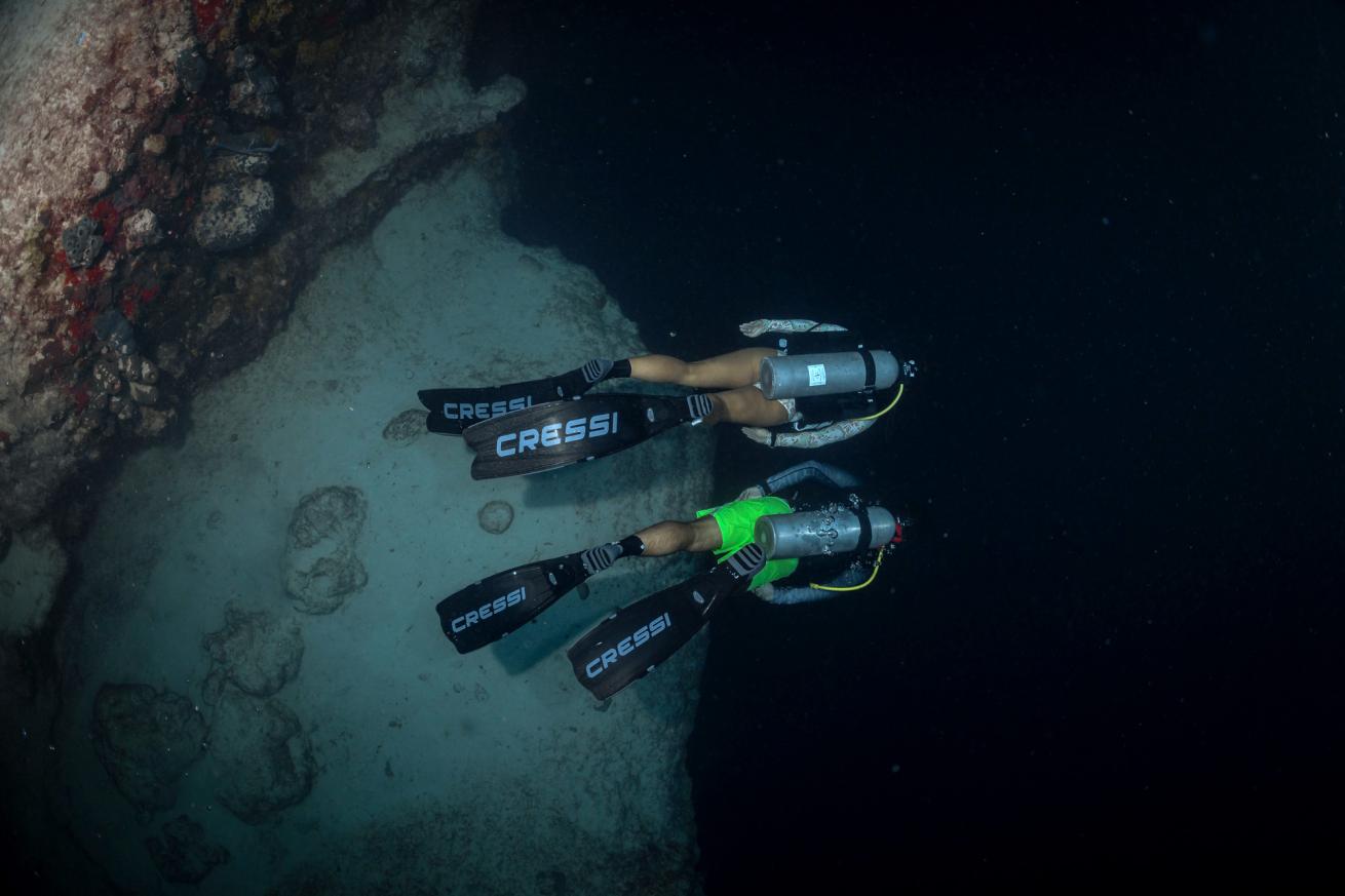Scuba divers explore a blue hole in the Exumas, Bahamas.