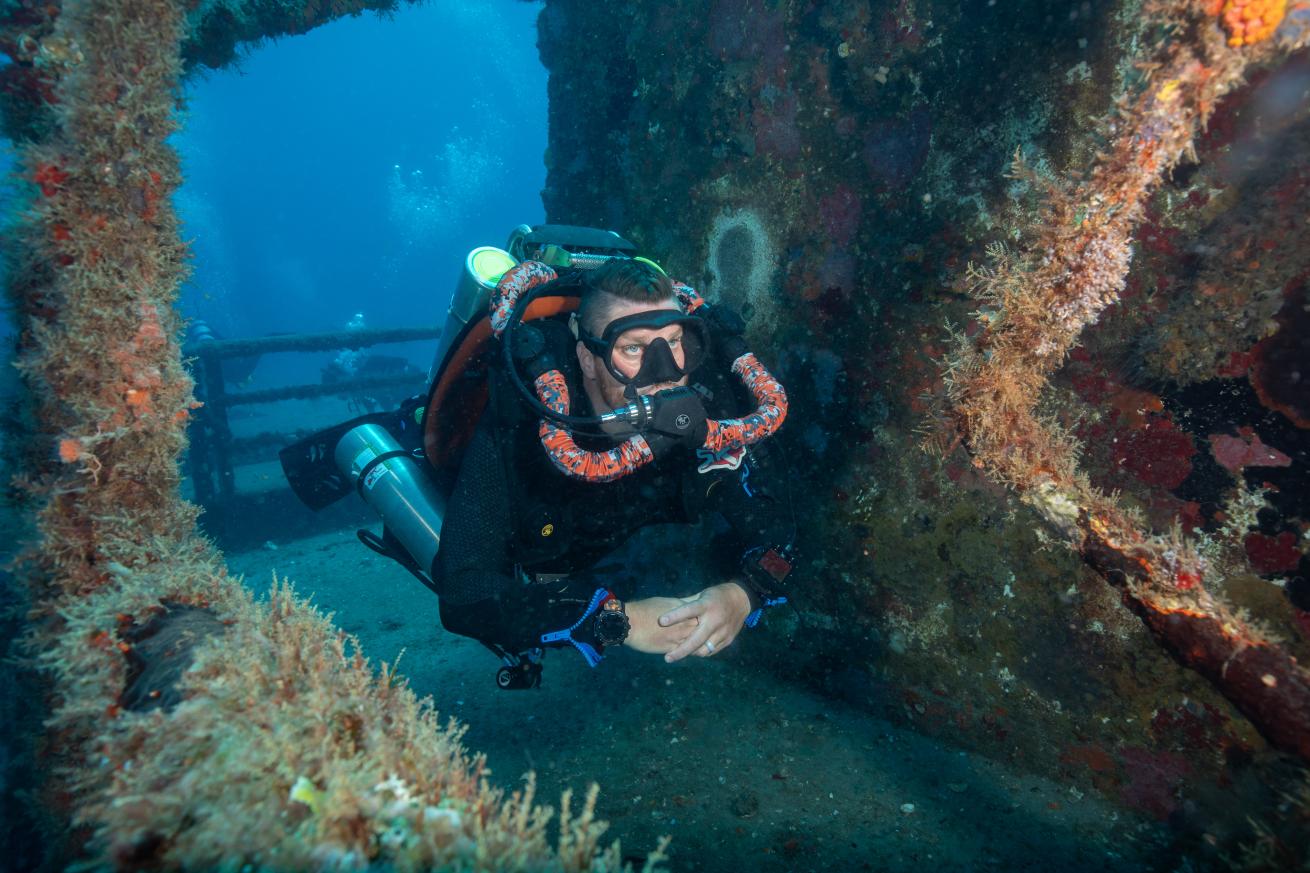 a rebreather diver swimming through a wreck