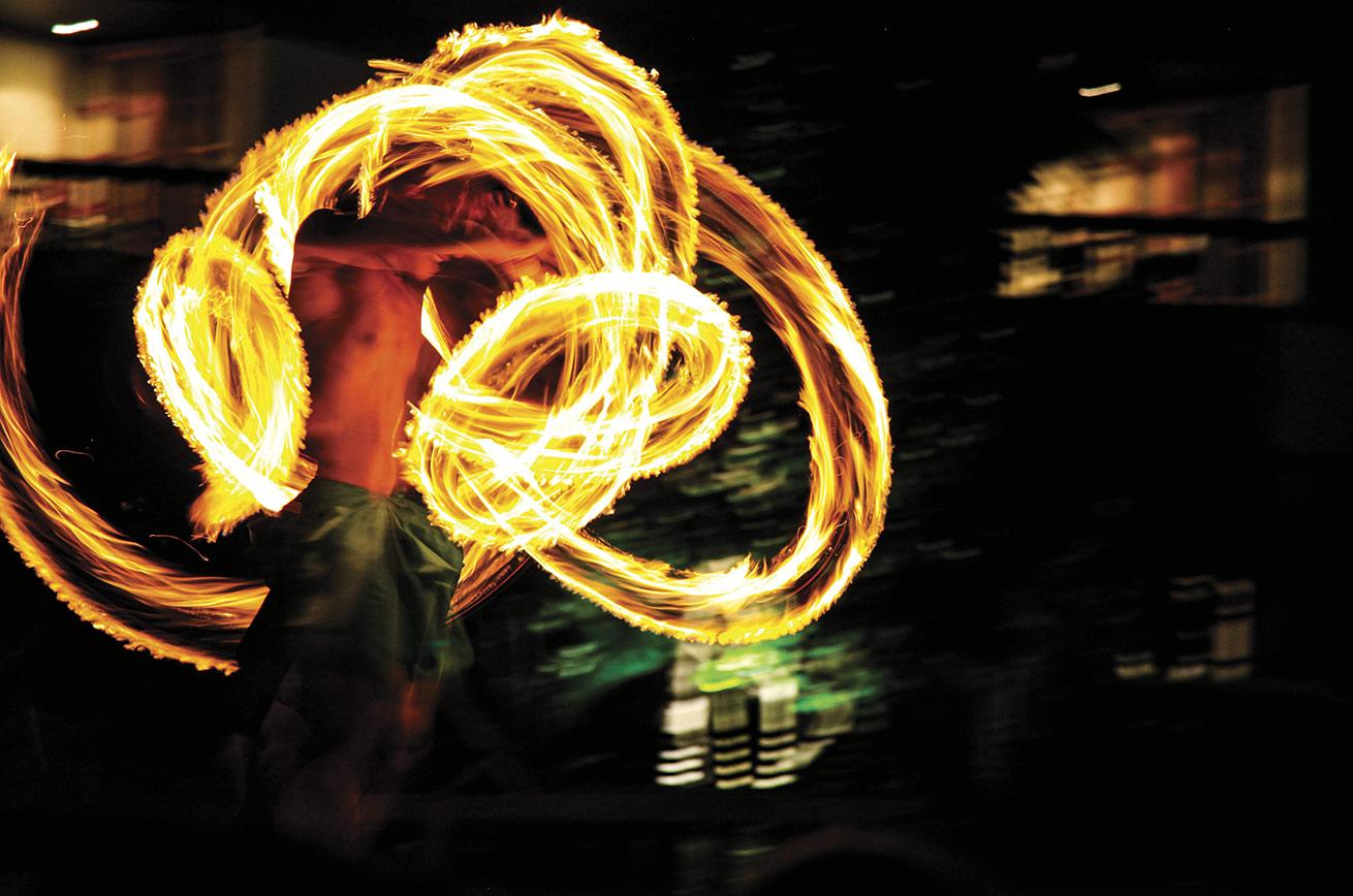 A skilled fire dancer spins his sticks of fire at impossible speeds.